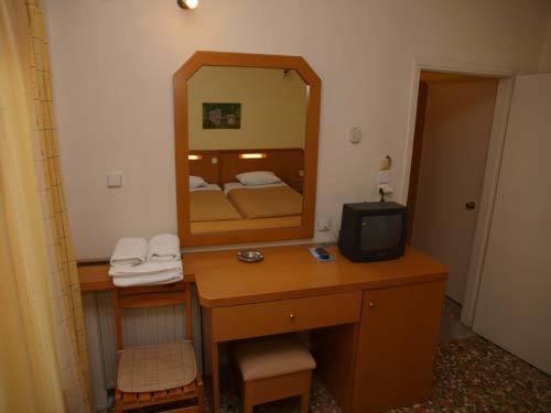 a bedroom with a desk with a mirror and a television at Hotel Markos in Ierissos