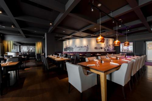 a restaurant with wooden tables and white chairs at elaya hotel stuttgart ludwigsburg ehemals Abacco by Rilano in Korntal-Münchingen