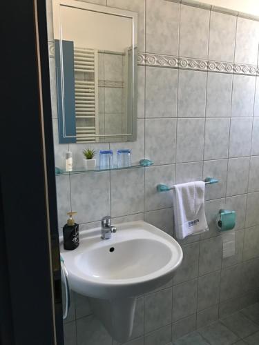 ein Badezimmer mit einem weißen Waschbecken und einem Spiegel in der Unterkunft Penzion Parkur in Hrobice