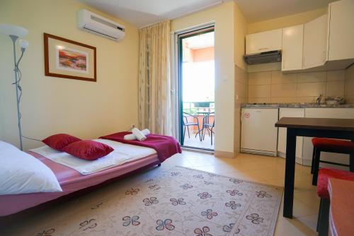 a bedroom with a bed with red pillows and a kitchen at Apartments Ivan in Zadar