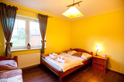 a yellow bedroom with a bed with dolls on it at Willa Ostoja in Świeradów-Zdrój