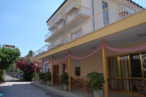 a yellow building with a balcony and tables and chairs at Hotel Perugini in Rimini