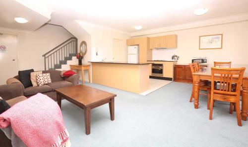 a living room and kitchen with a couch and a table at Caulta Apartments in Sydney