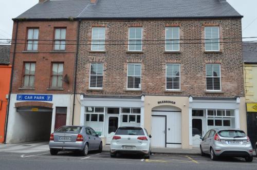 dois carros estacionados em frente a um edifício de tijolos em Blessings Studio Apartments em Cootehill