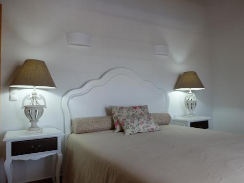 a bedroom with a white bed with two lamps at Vales do Alentejo in Bicos