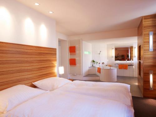 a bedroom with a large white bed and a bathroom at Hotel VICTORIA Nürnberg in Nürnberg