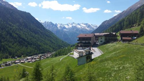 a village in a valley with mountains in the background at Pension Winnebach in Längenfeld