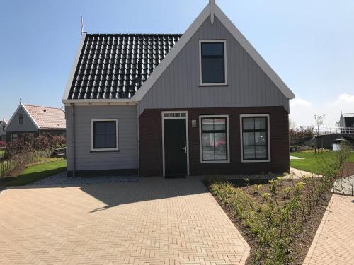 a brown house with a black door on a driveway at Luxurious Water Villa in Uitdam