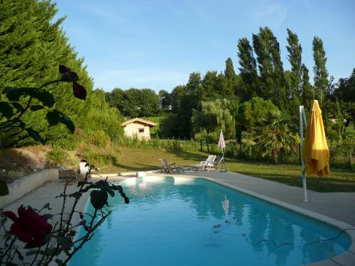 una piscina con sombrilla y sillas amarillas en La Source, Vegetarian Guest House, en Chabeuil