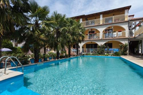 a pool in front of a building with palm trees at Apartments Paradis in Rovinj