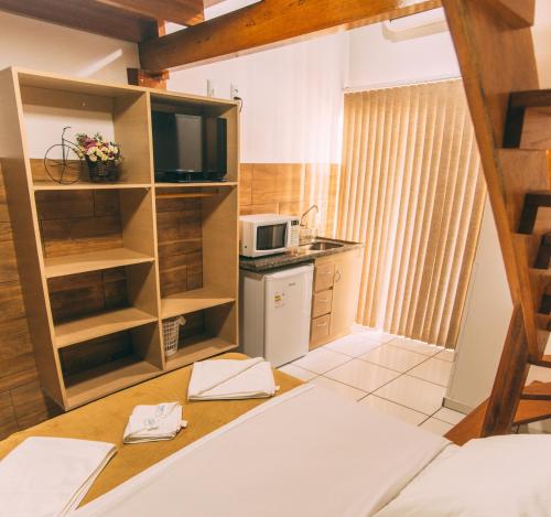 Kleines Zimmer mit einer Küche und einer Mikrowelle. in der Unterkunft Pousada Bronzatto in Garopaba