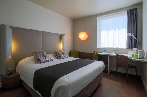 カルカソンヌにあるカンパニール カルカソンヌ エスト - ラ シテの大きなベッドとデスクが備わるホテルルームです。