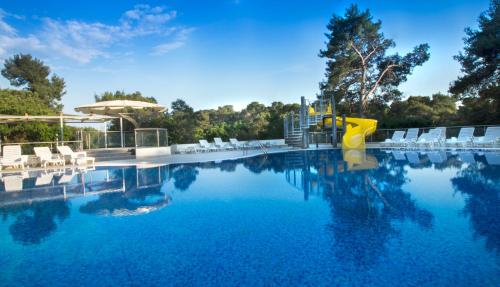 a swimming pool with a slide in the middle at Hotel Adria in Biograd na Moru