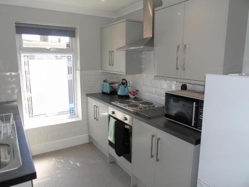 a kitchen with white cabinets and a stove top oven at Jeffersons Hotel & Serviced Apartments - The Steel Works in Barrow in Furness