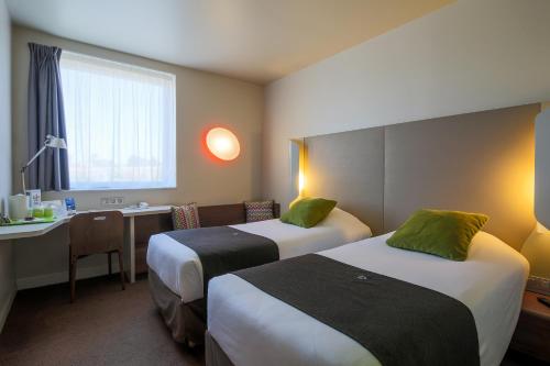 a hotel room with two beds and a desk at Campanile Carcassonne Est - La Cité in Carcassonne