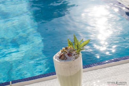 a drink with a plant in it next to a swimming pool at Silver Hotel in Oradea