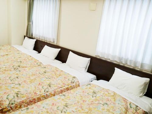 a hotel room with three beds and a window at Osaka Academia in Osaka
