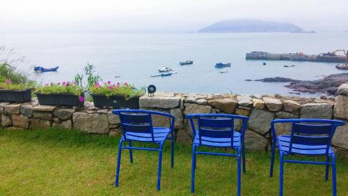 three blue chairs sitting on the grass near the water at B&B of Blueshine in Beigan