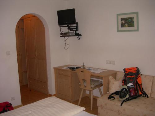 a bedroom with a desk and a bed with a backpack at Berggasthof Stern in Predoi