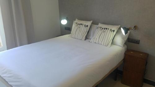a bed with white sheets and pillows in a room at The Lights City Rooms in Málaga