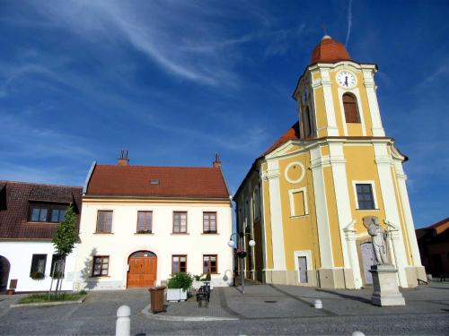 un edificio amarillo con una torre de reloj delante de él en Apartmán U Kostela, en Veselí nad Moravou