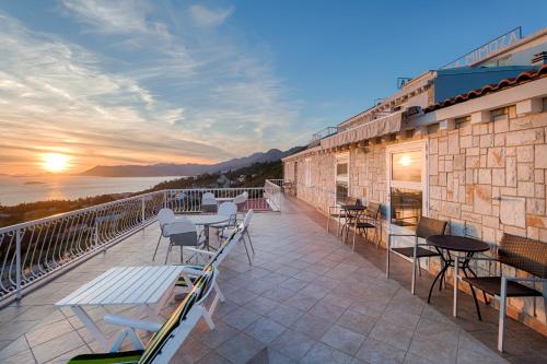 a balcony with tables and chairs on a building with the sunset at Villa Mimoza in Cavtat
