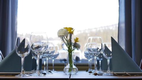a table with wine glasses and a vase with a flower at Rondane Hytter og Leiligheter in Otta