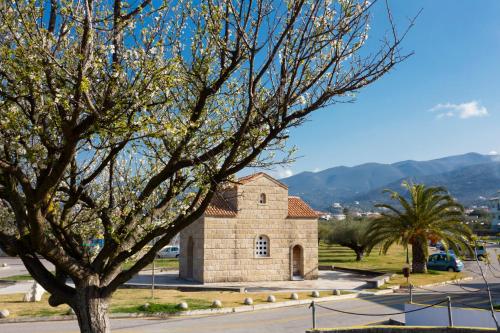 a small stone church with a tree in the foreground at Elite City Resort in Kalamata