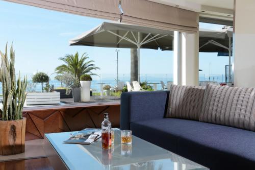 a dining table with a blue couch and an umbrella at Elite City Resort in Kalamata