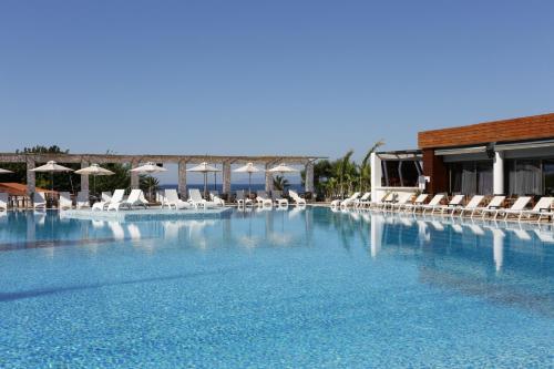 ein großer Pool mit Stühlen und Sonnenschirmen in der Unterkunft Elite City Resort in Kalamata
