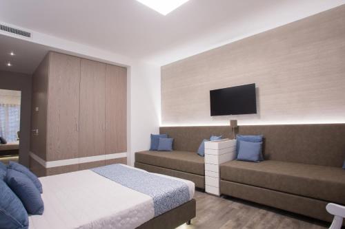 a bedroom with a bed and a couch and a tv at Hotel Liberty Beach - Parking & Beach in Riccione