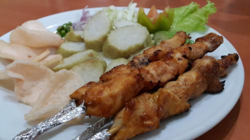 a plate of food with chicken skewers and chips and salad at Sarasvati Borobudur in Borobudur