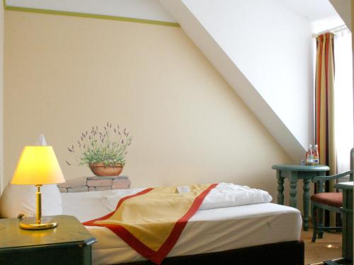 a bedroom with a bed and a table with a lamp at Hotel Speeter in Weisenheim am Berg