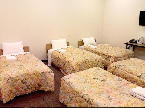 a hotel room with four beds and a table at Osaka Academia in Osaka