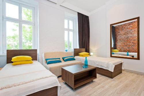 een kamer met 2 bedden, een bank en een spiegel bij MoHo S in Wrocław