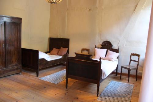 a room with two beds and a chair at Lindstedter Gutsstuben in Gardelegen