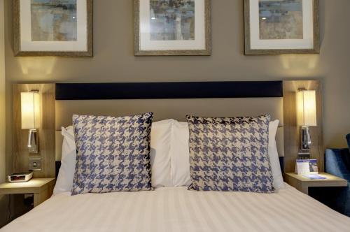 a bedroom with a bed with blue and white pillows at Linton Lodge a BW Signature Collection Hotel in Oxford