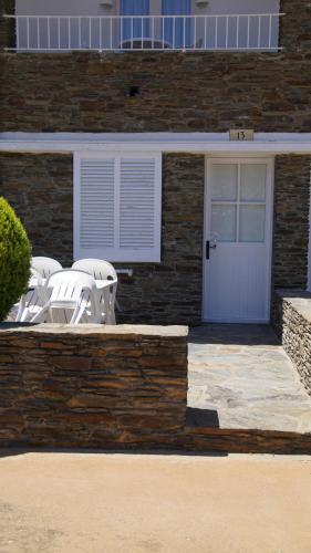 a patio with white chairs and a white door at Hotel Calina in Cadaqués