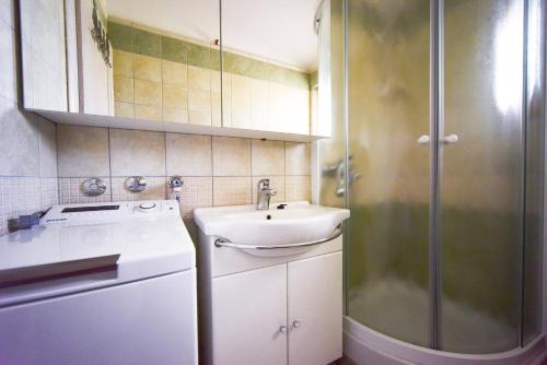 a bathroom with a sink and a washing machine at Apartments Villa Perla in Rovanjska