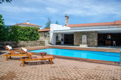 a swimming pool with two chairs and a house at Casa de Campo dos Távoras in Mirandela