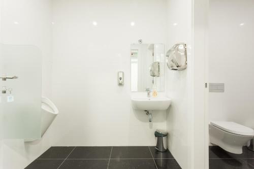 a white bathroom with a toilet and a sink at Hotel Capital Lisboa in Lisbon