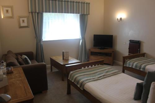 a living room with two beds and a tv at Nant Ddu Lodge Hotel & Spa in Merthyr Tydfil