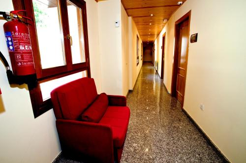 a red couch sitting in a hallway in a building at Hotel Montseny in Espúy