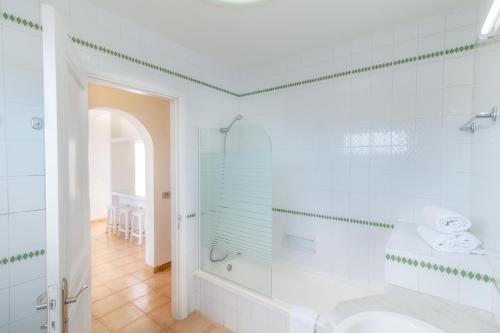 a white bathroom with a shower and a sink at Apartamentos LIVVO Las Gaviotas in Puerto del Carmen