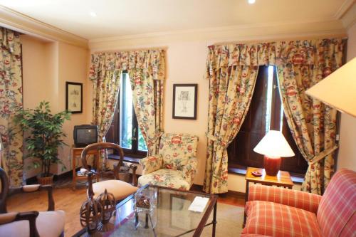 uma sala de estar com um sofá e duas janelas em Casavillena Apartamentos Turísticos na Segóvia