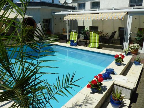 a swimming pool with flowers and plants next to a house at Pension Münch "Am Anger" in Neuseußlitz