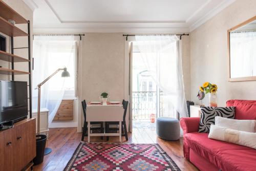 リスボンにあるCozy Apartment in historic centerのリビングルーム(赤いソファ、テーブル付)
