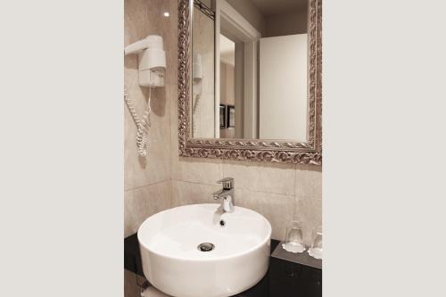 y baño con lavabo blanco y espejo. en c-hotels Diplomat, en Florencia