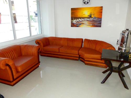 a living room with two orange couches and a table at Hotel El Emigrante in Puerto Colombia