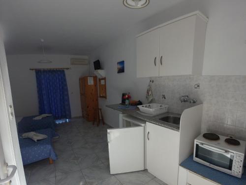 a kitchen with white cabinets and a sink and a microwave at Irene Studios in Arillas